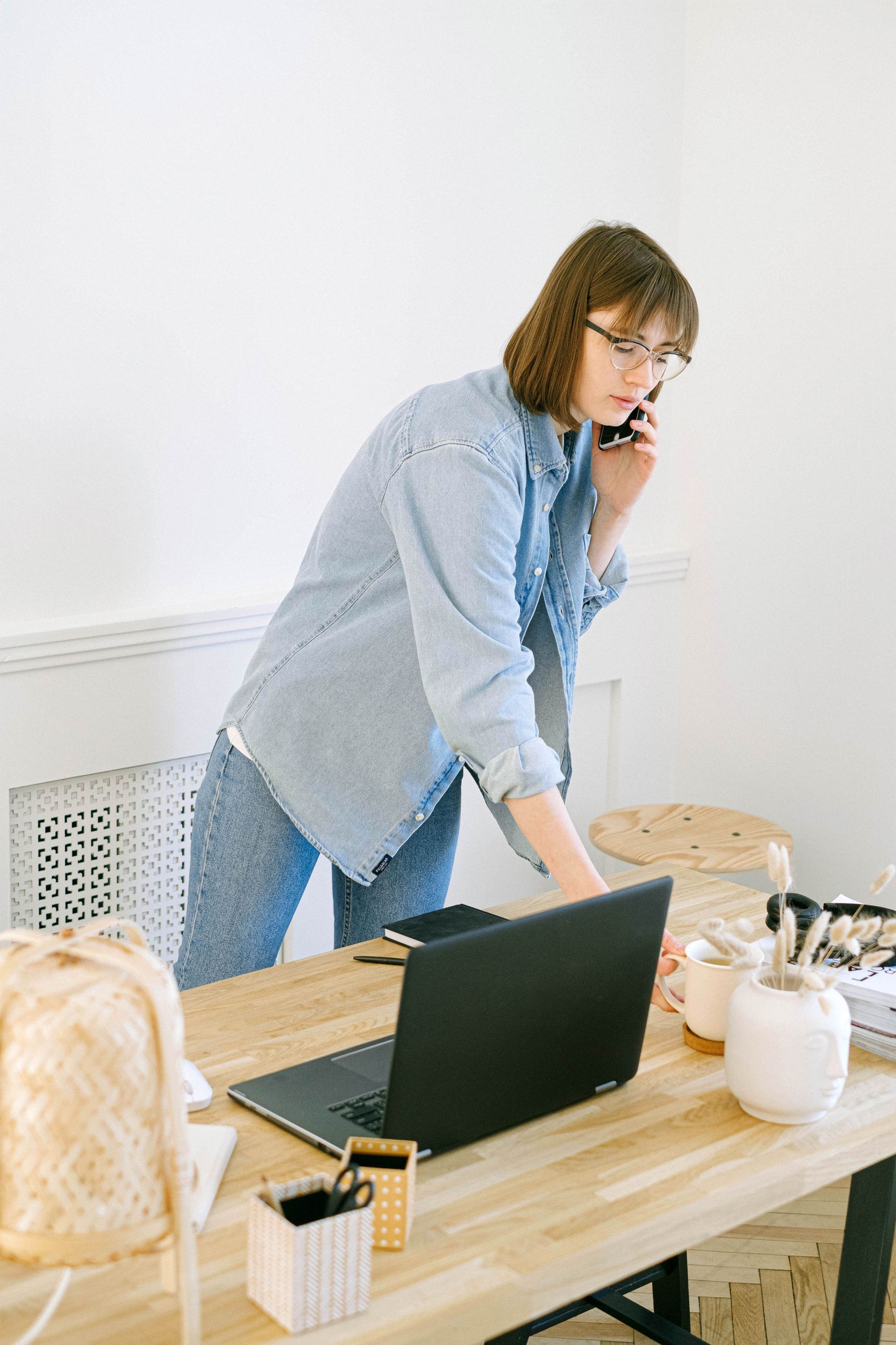 Frau telefoniert am Schreibtisch mit Laptop